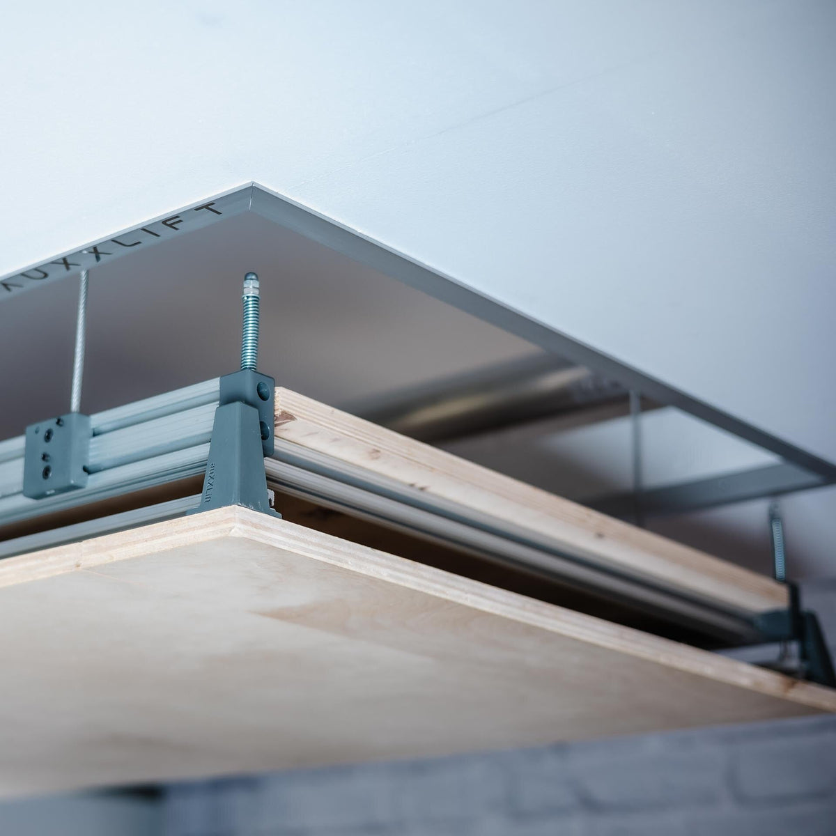Close-up of the Auxx Attic-Lift aluminium frame and plywood decking at the ceiling