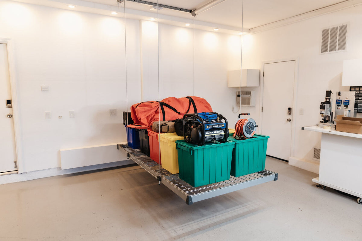 Auxx-Lift platform lowered in a garage with storage bins and equipment loaded on the deck