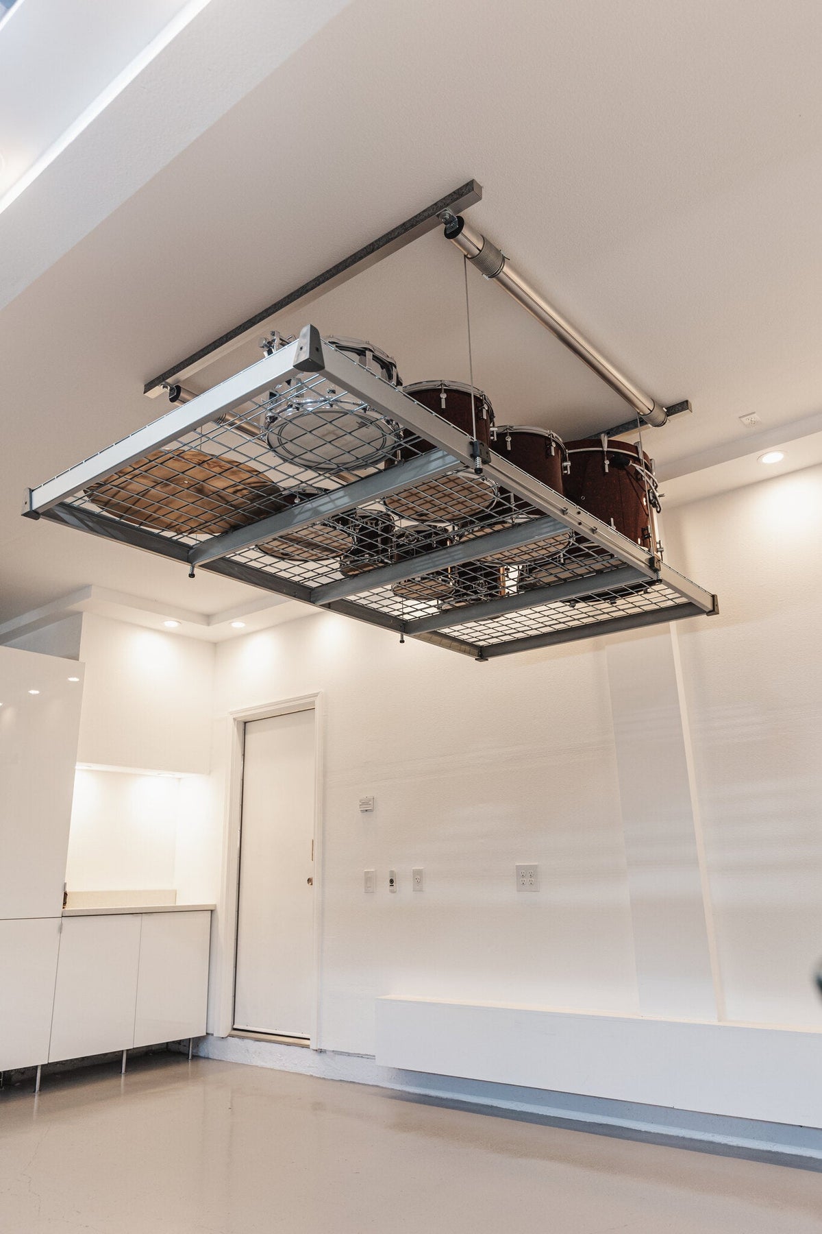 Auxx-Lift platform raised flat against the garage ceiling with stored items, clearing the floor below