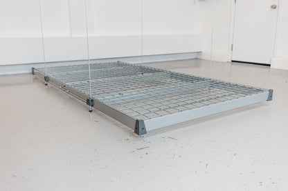 Empty Auxx-Lift platform at floor level showing the galvanized wire mesh deck and steel C-channel frame